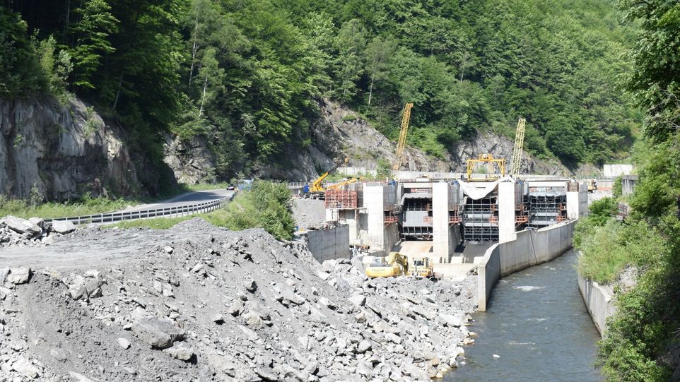 Romanian hydroelectric power station on a small river surrounded by green trees