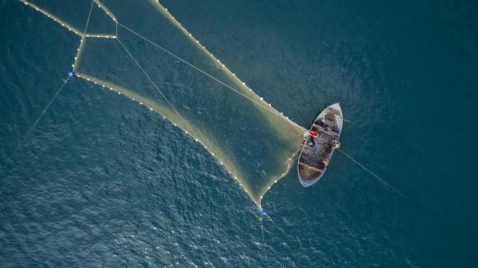 Kleines Fischerboot mit großem, ausgeworfenen Fangnetz 
