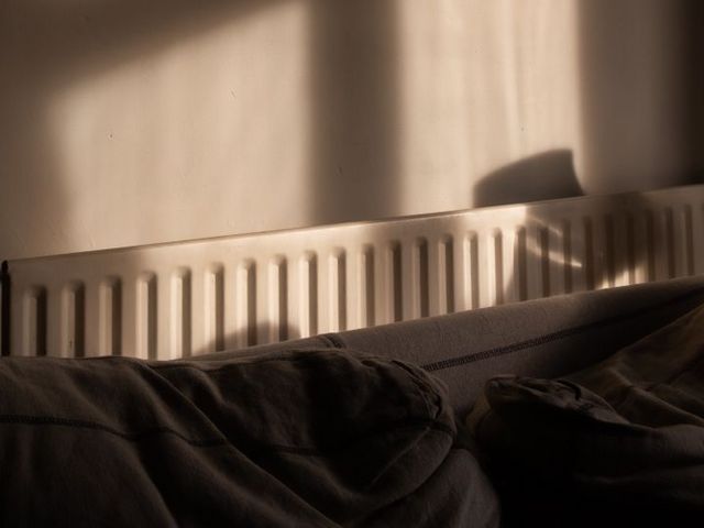 Heizkörper hinter dem Kopfende eines Bettes