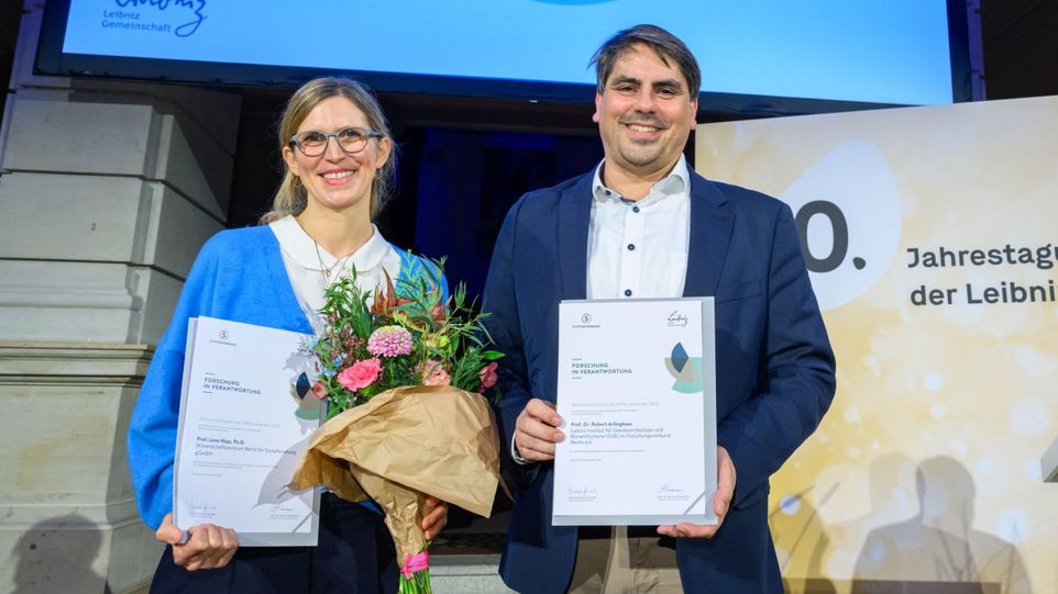 Preisträgerin und Preisträger mit Blumen und Urkunden