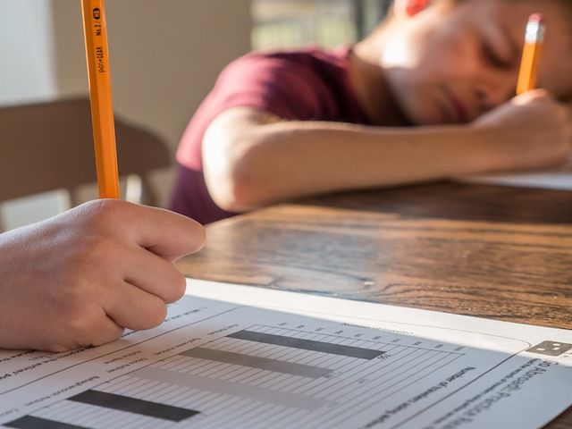 Nahaufnahme der Hand eines Kindes, welches Schulaufgaben bearbeitet