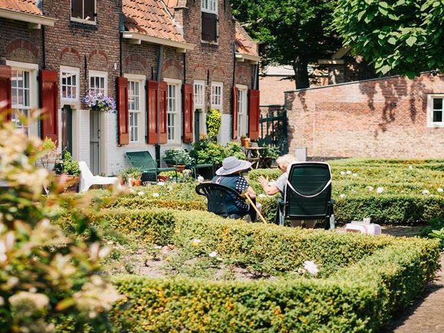 Row houses with well-kept front gardens, in one of them two elderly ladies are sitting and talking.