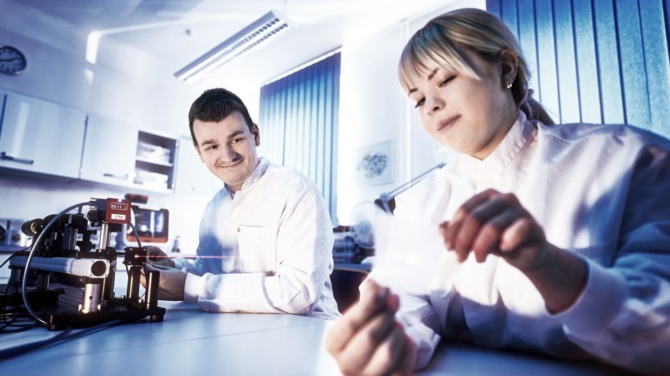 Young man and woman in white coats in the lab