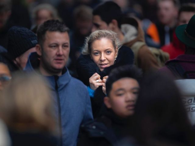 Menschenmenge, das Licht fällt auf das Gesicht einer Frau