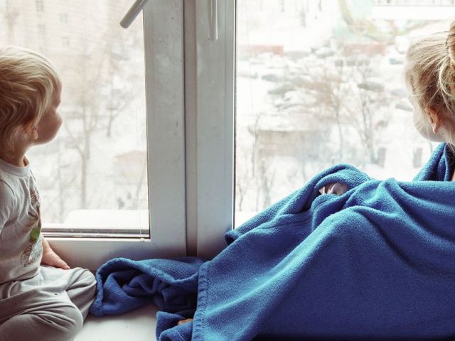 Zwei Kinder schauen aus dem Fenster