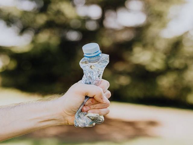 Zerknüllte Plastikflasche in der Hand eines Mannes