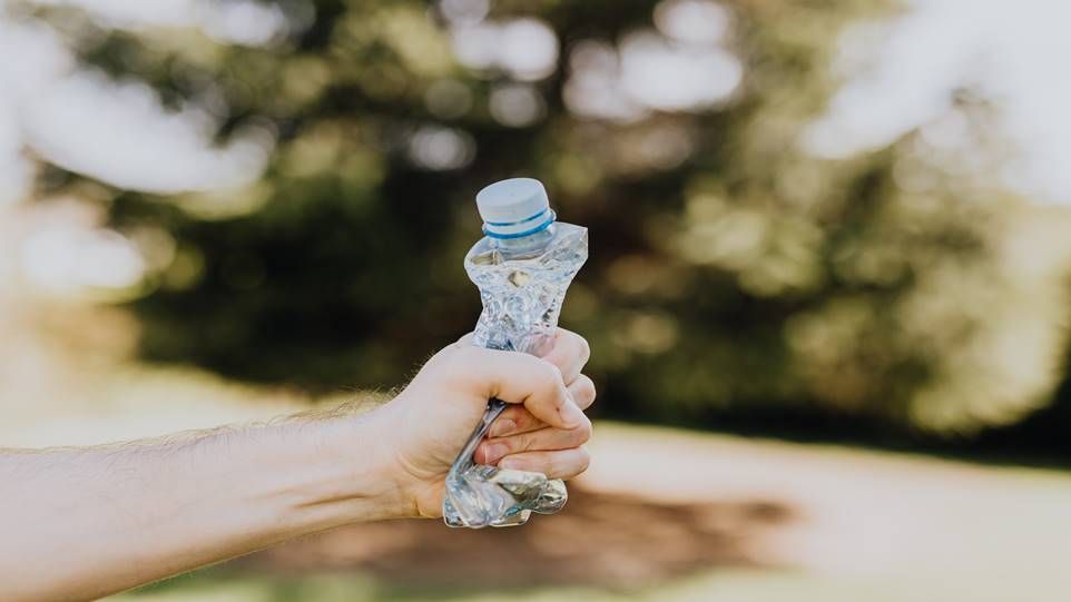 Zerknüllte Plastikflasche in der Hand eines Mannes