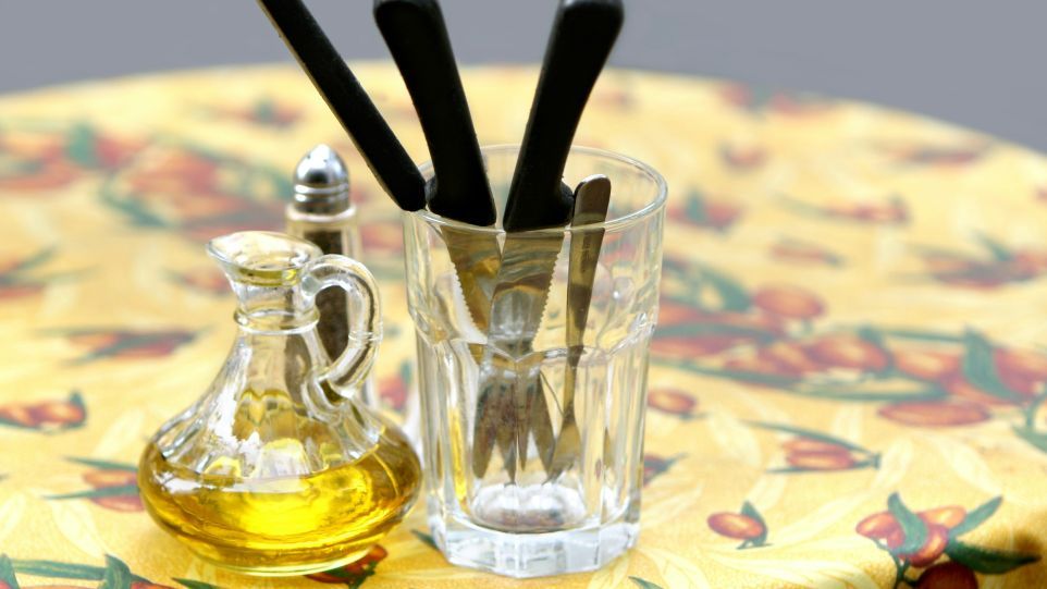 Ein Tisch gedeckt mit einem Ölkännchen, einem Pfefferstreuer und Besteck