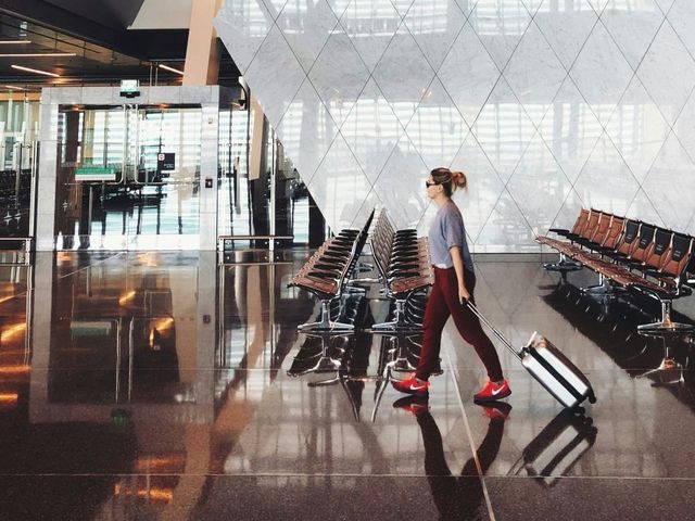 Frau mit Rollkoffer im Flughafengebäude