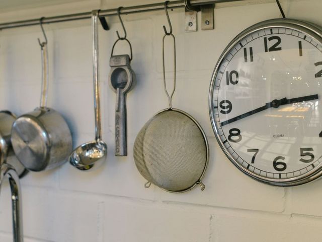 Wanduhr neben Töpfen und Küchengerät